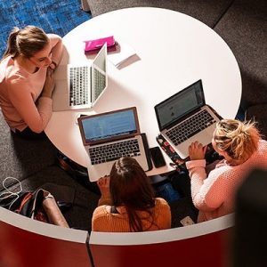 Students working on laptops around a round table