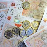 Close-up of pound coins on ten pound notes.