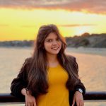 Student learning on the pier with the sunset in the distance
