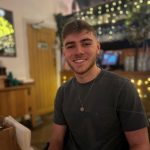 Jack is smiling at the camera with fairy lights behind him
