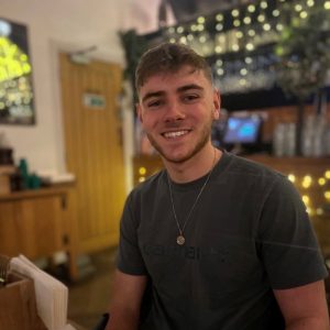 Jack is smiling at the camera with fairy lights behind him
