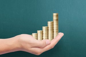 A hand holding an increasing stack of coins