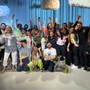 A large group of people posing for the photo, everyone is smiling and some people have their hands in the air