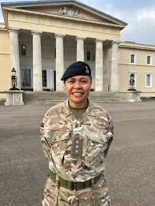 Helen Tokaiqali standing outside of a building with pillars in her military uniform