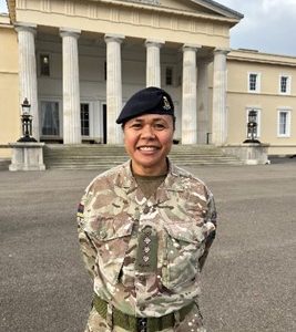 Helen Tokaiqali standing outside of a building with pillars in her military uniform