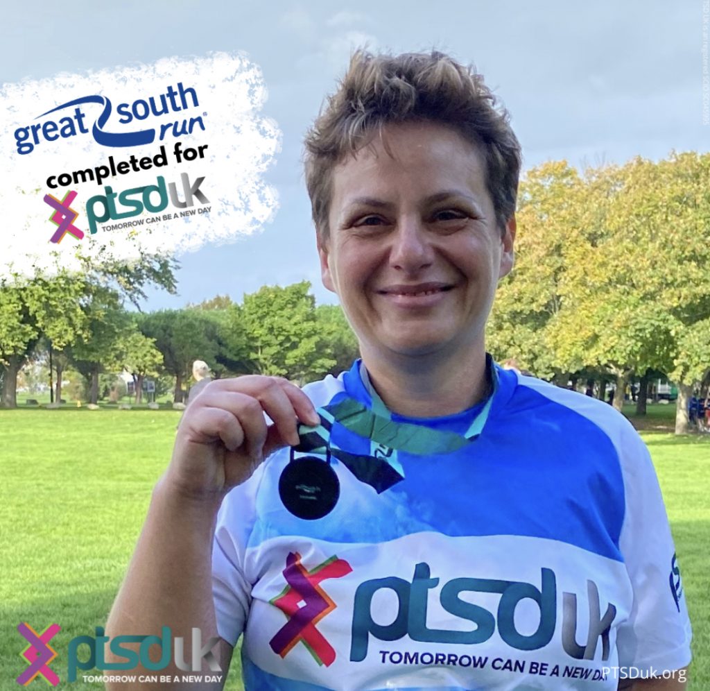 Sarah smiles at the camera after completing the great south run and she is holding up her medal around her neck