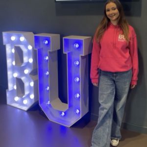 Student ambassador next to BU sign.