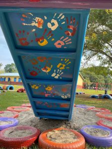Turing scheme - Play Action Uganda - under a slide with painted handprints